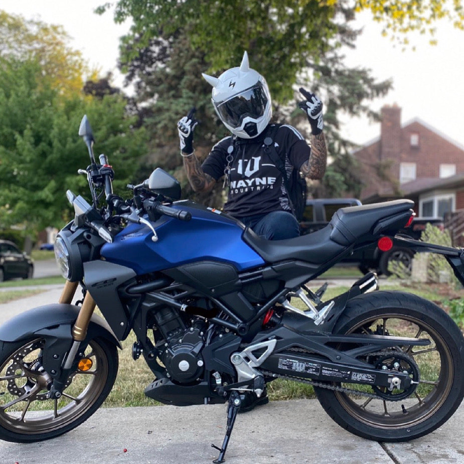 Large white horns on a motorcycle helmet worn by a man behind a blue motorcycle