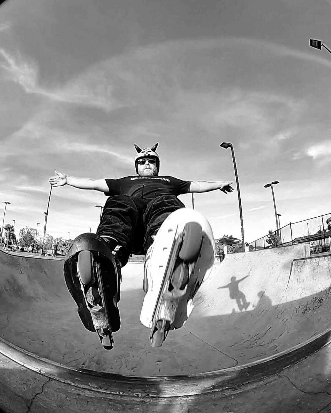 Rollerblader with large black devil horns at the skate park in mid air