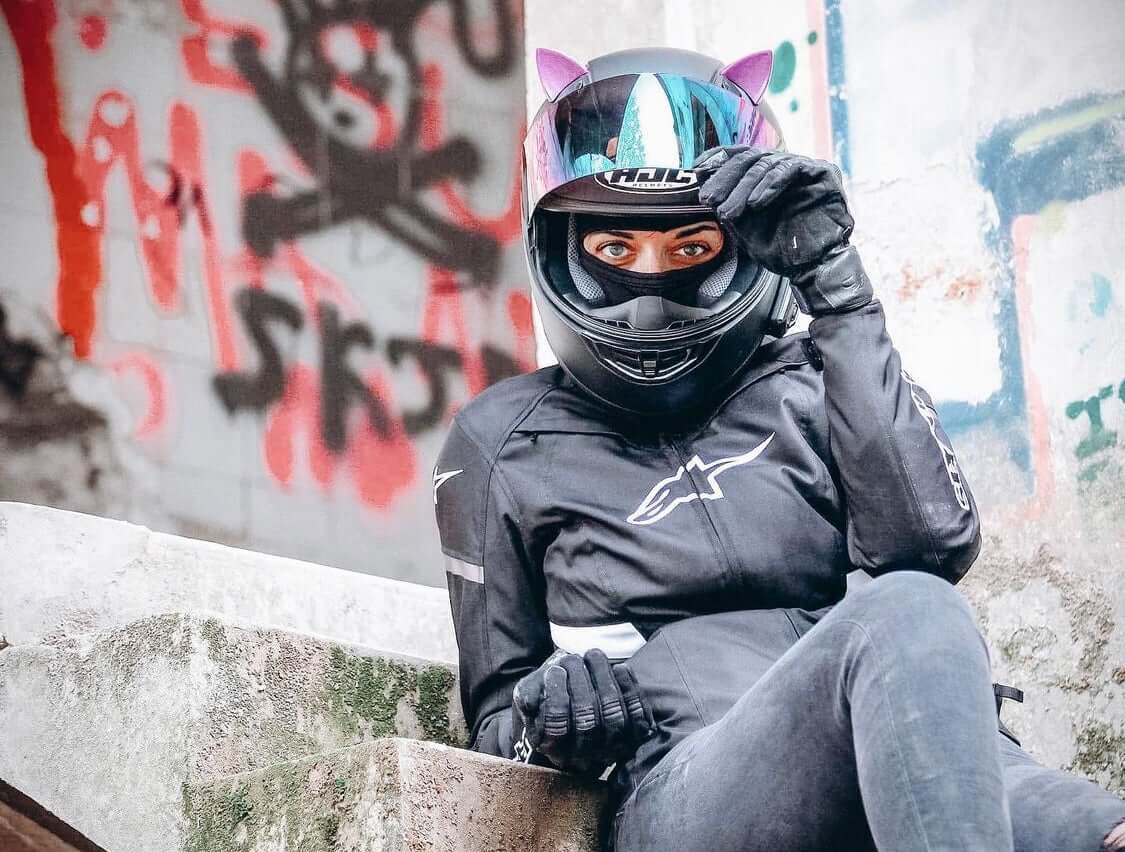 Woman sitting on stairs with pink cat ears on her motorcycle helmet