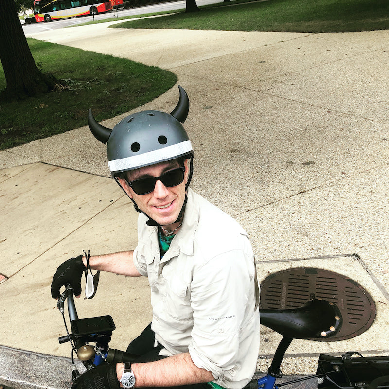 Bike commuter riding with a custom helmet featuring black Helmet Flair horn accessories