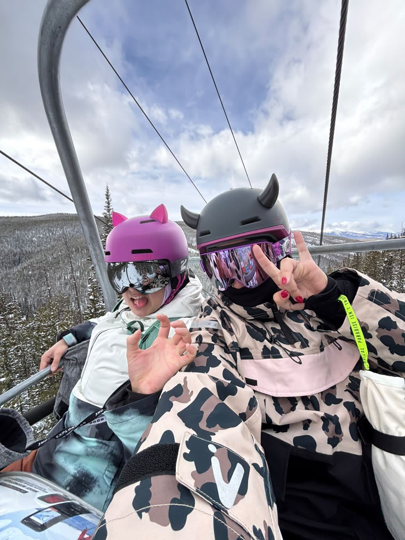 Two people riding a chair lift wearing helmets with Helmet Flair Softeez accessories for fun winter style