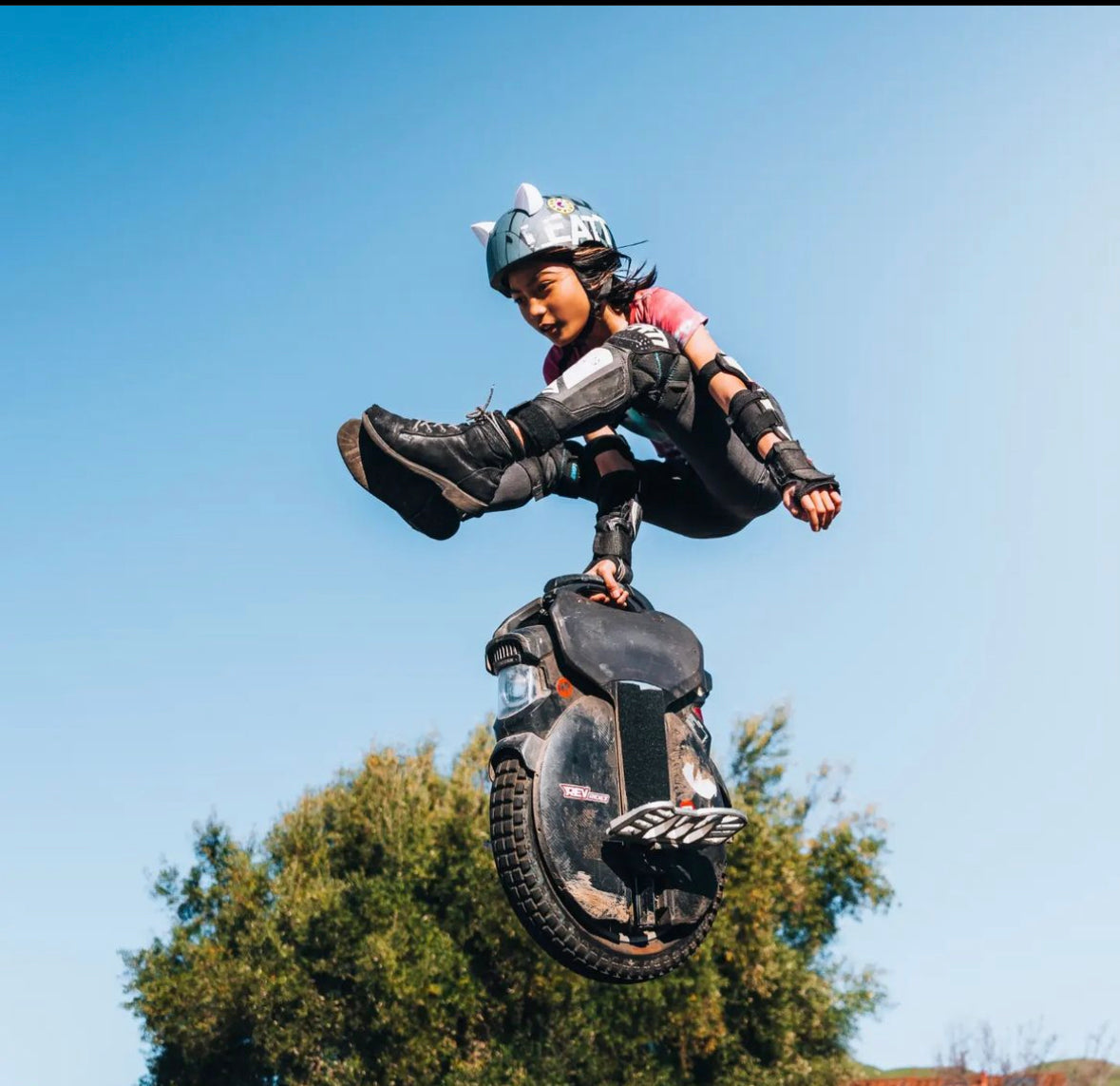 EUC rider jumping with white kitty ear Helmet Flair accessories on her helmet for fun style and visibility