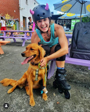 Rollerblader with small pink horns on her helmet petting a dog