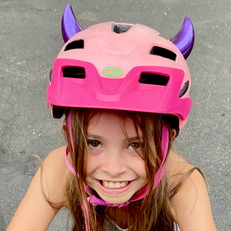 Girl wearing small purple horns on her bicycle helmet