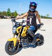 Woman with small purple horns on her motorcycle helmet on a yellow motorcycle