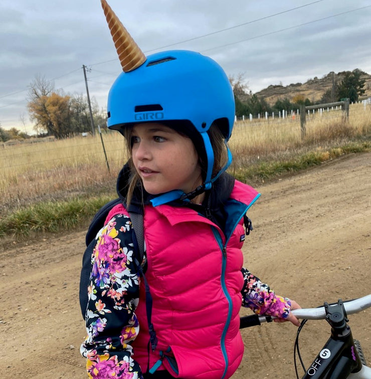 Girl wearing gold unicorn horn on her bicycle helmet