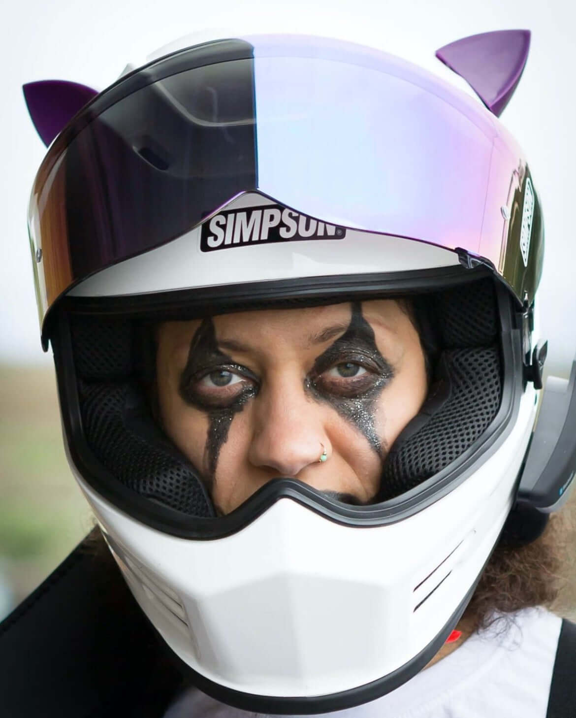 Purple cat ears on a motorcycle helmet with cool halloween makeup on a woman&