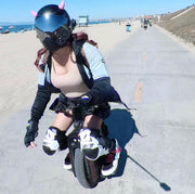 Woman riding an electric unicycle wearing small pink horns on her helmet