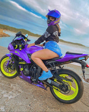 Woman with small purple horns on her motorcycle helmet on a purple motorcycle