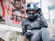 Woman sitting on stairs with pink cat ears on her motorcycle helmet